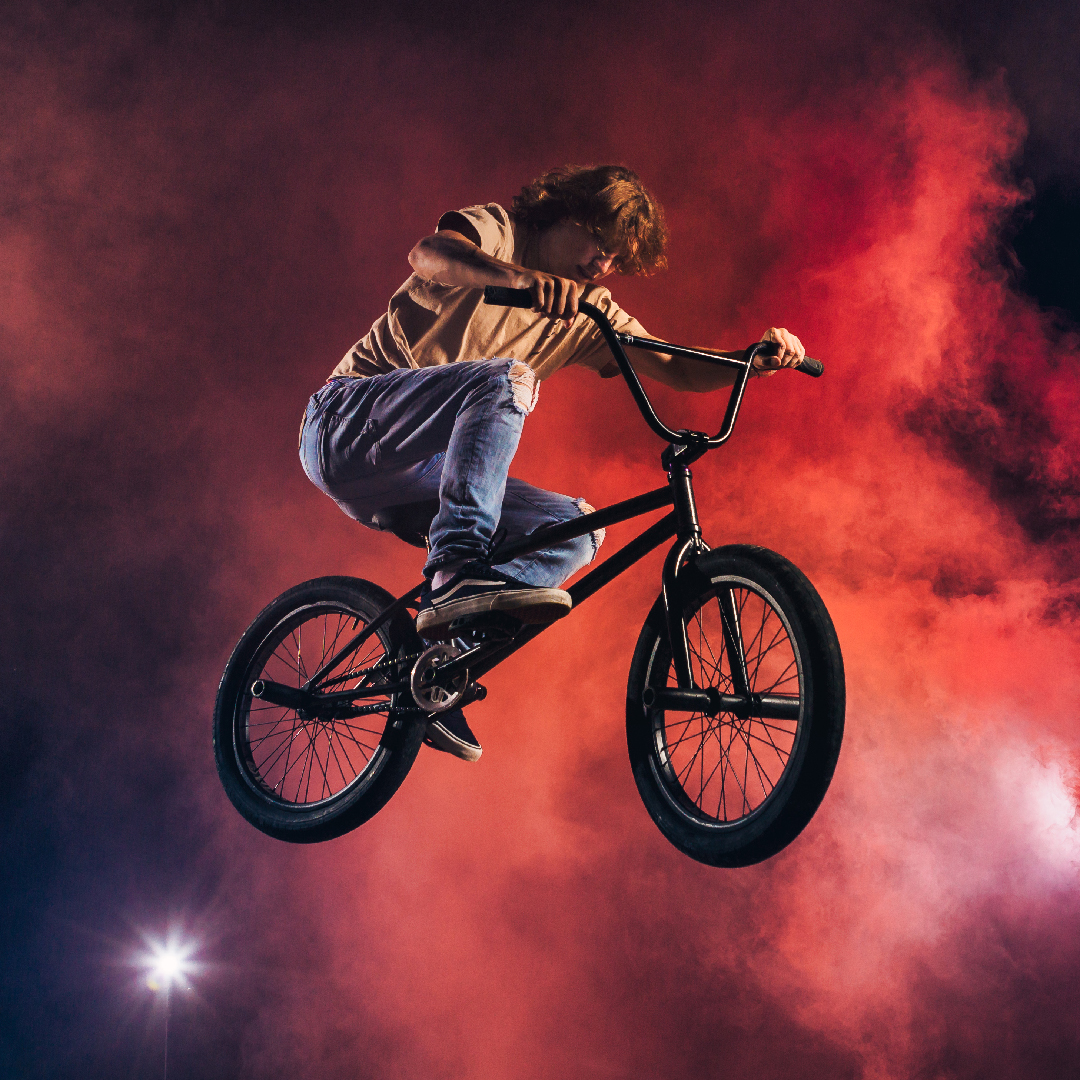 BMX rider airborne against a cloud of red smoke
